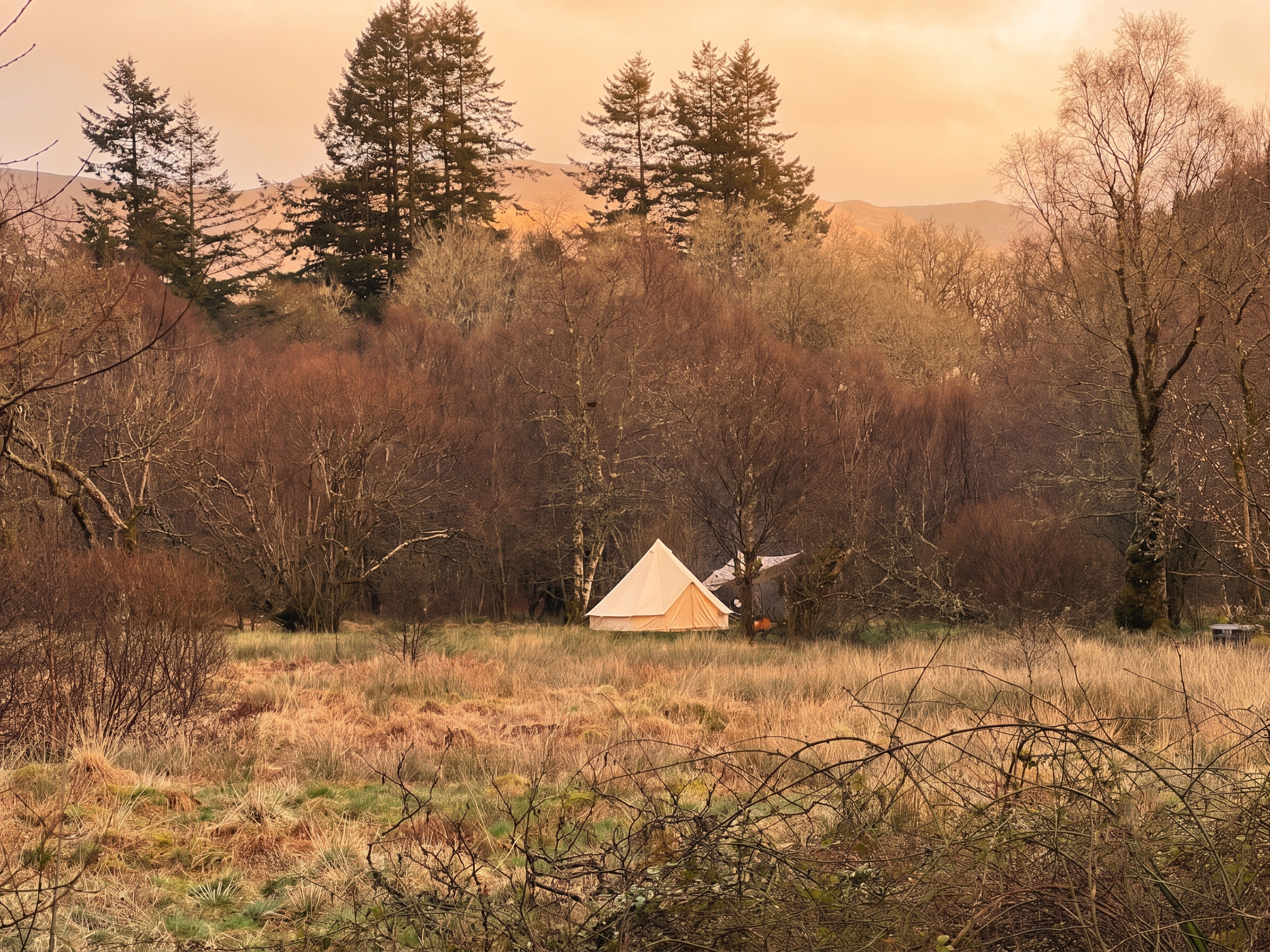 Campfire cooking setup and packing gear beside Scottish loch
