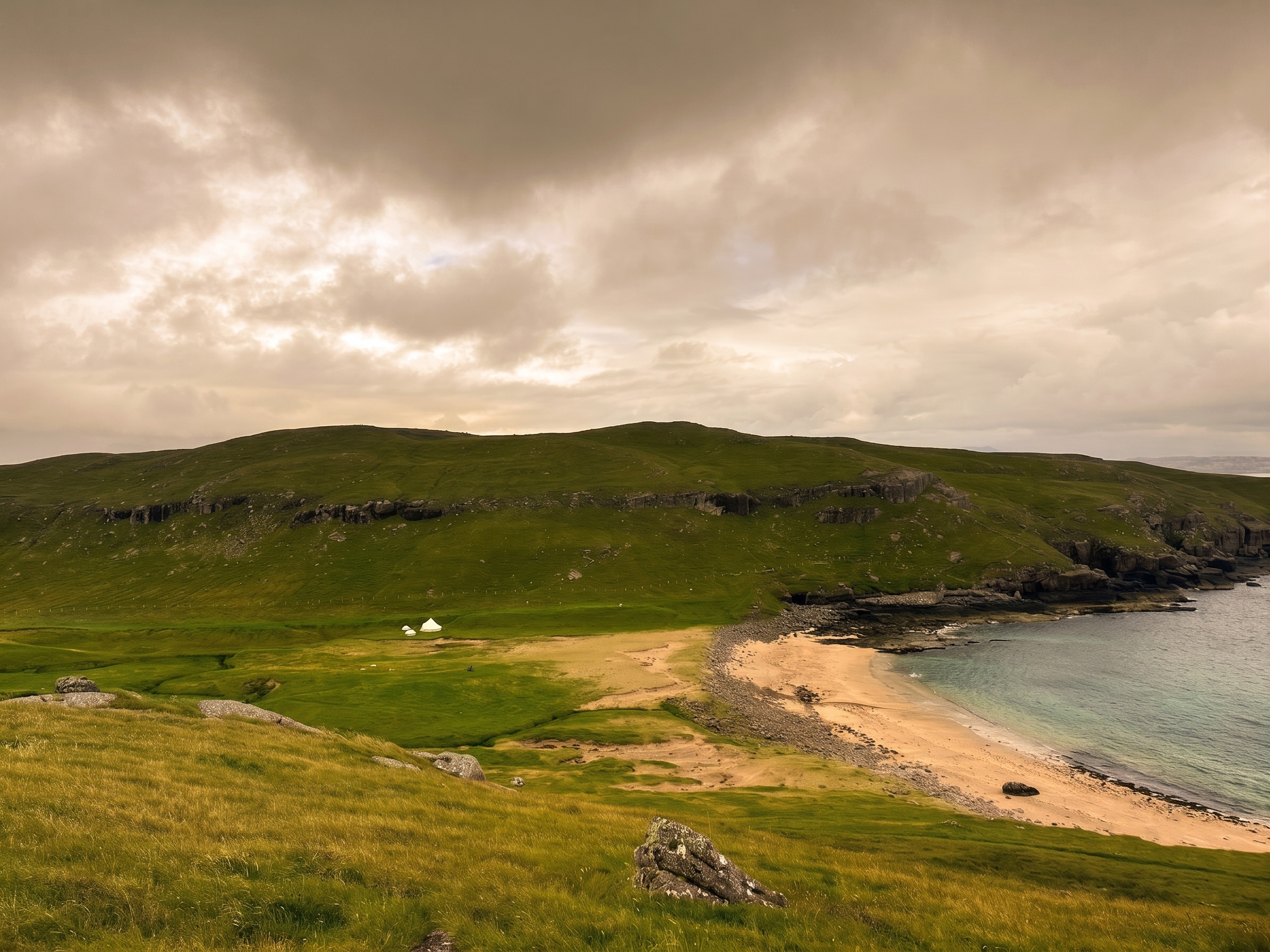 White bell tent pitched on coastal Scottish cove