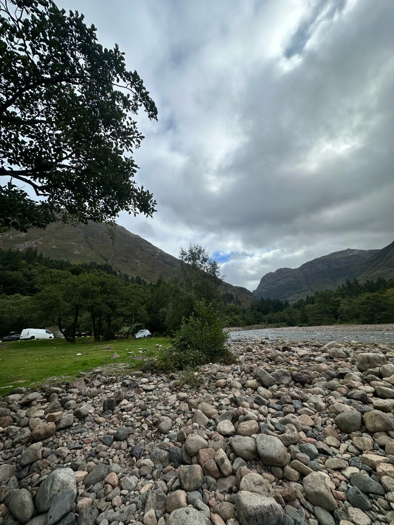 Riverbank at Red Squirrel with the tent in the trees and a van on the grass