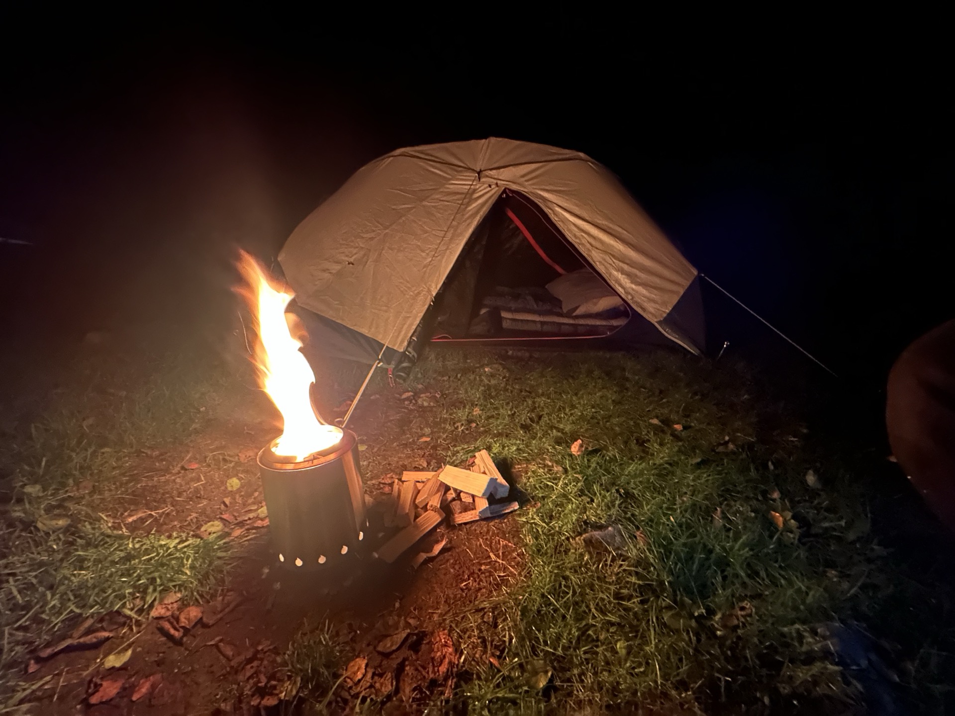 Decathlon two-man pop-up tent with the door open and a stove burning