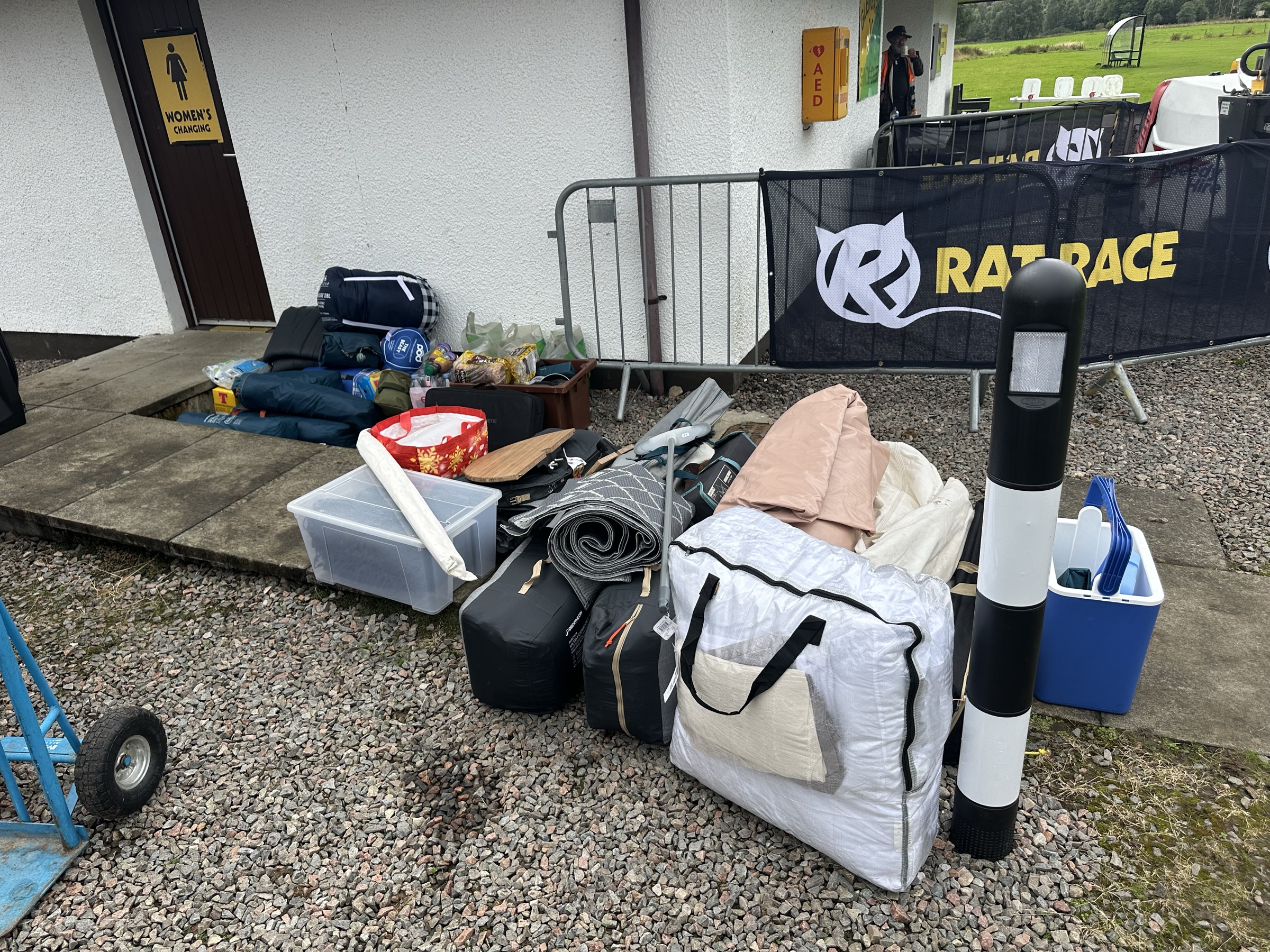Hire kit piled on gravel beside a Rat Race barrier and the women’s changing rooms